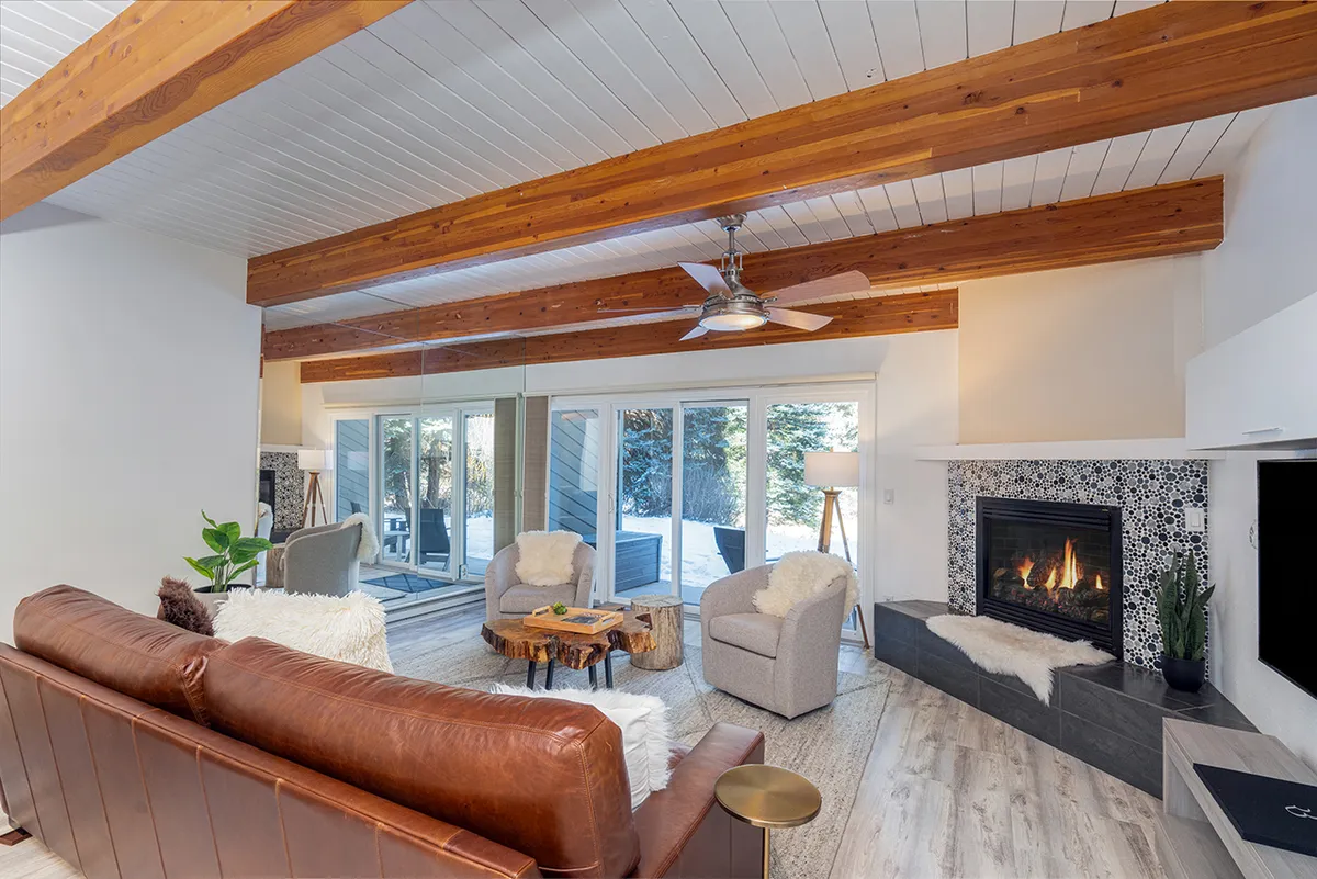 A warm, welcoming living area with a leather sofa, fireplace, and large windows that let in plenty of natural light. The space feels open and inviting, ideal for both relaxation and family gatherings.